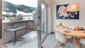 A modern dining area with a large window overlooking a snowy mountain landscape. - Das Georgen, Kitzsteinhorn by Interhome (Bruck)