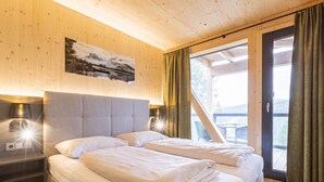 Habitación de hotel con dos camas, paredes de madera, un cuadro y vistas al exterior.
