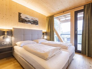 Camera d'albergo con due letti, pareti in legno, un quadro e vista sull'esterno.