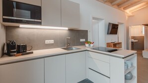 A modern kitchen with white cabinetry, a built-in microwave, and a coffee maker.