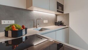 A modern kitchen with a black countertop, stainless steel sink, and a built-in oven. - Das Georgen, Maiskogel by Interhome (Bruck)
