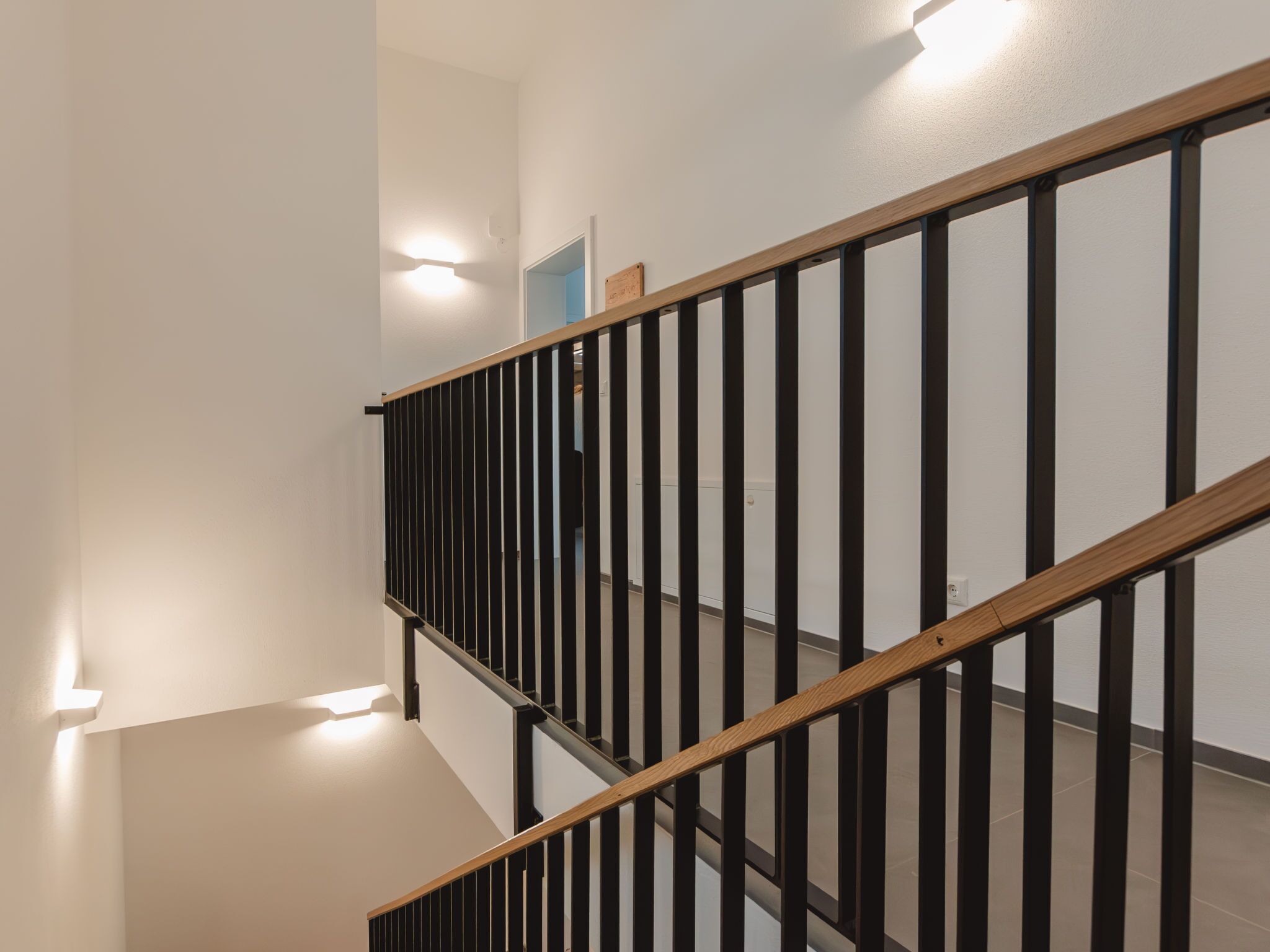 Una escalera moderna con barandillas negras y peldaños de madera.