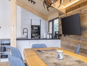 A modern kitchen with a built-in oven, a coffee machine, and a large window.