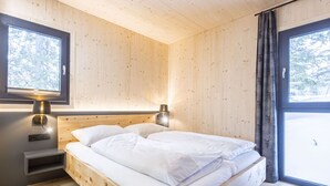 Un dormitorio de cabaña de madera con una cama, lámparas de noche y una ventana.