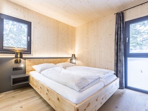 Une chambre dans une cabane en bois, avec un lit, des lampes de chevet et une fenêtre.