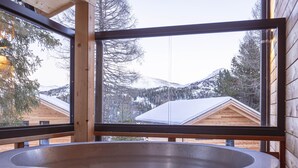 Una cabaña de madera con un ventanal grande y un jacuzzi.