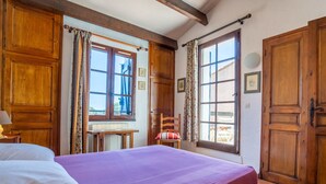 Ein Schlafzimmer mit Bett, Holzschrank und einem Fenster mit Vorhängen.