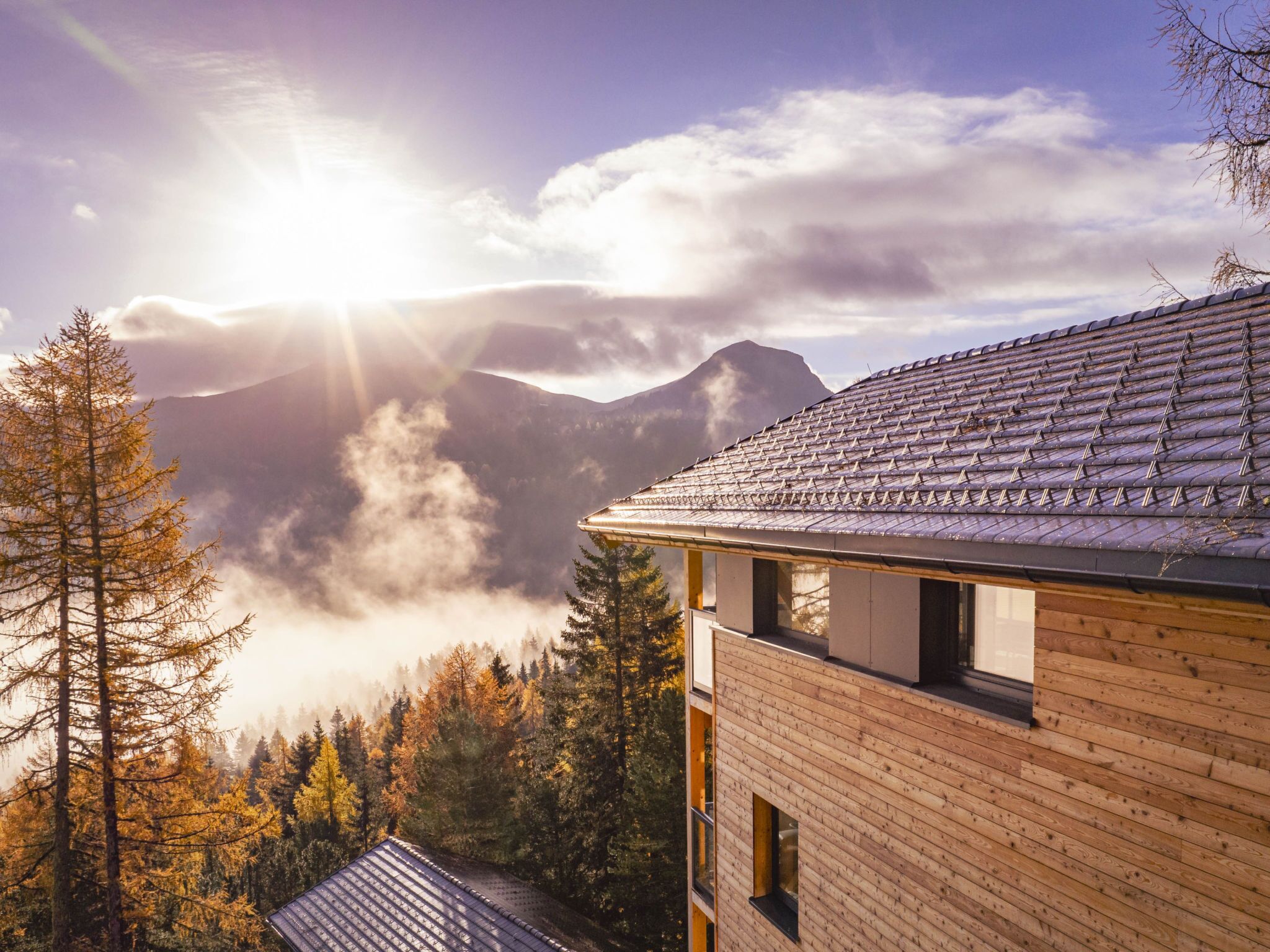 Eine Bergingerhütte mit geneigtem Dach, umgeben von Wald und Bergen.