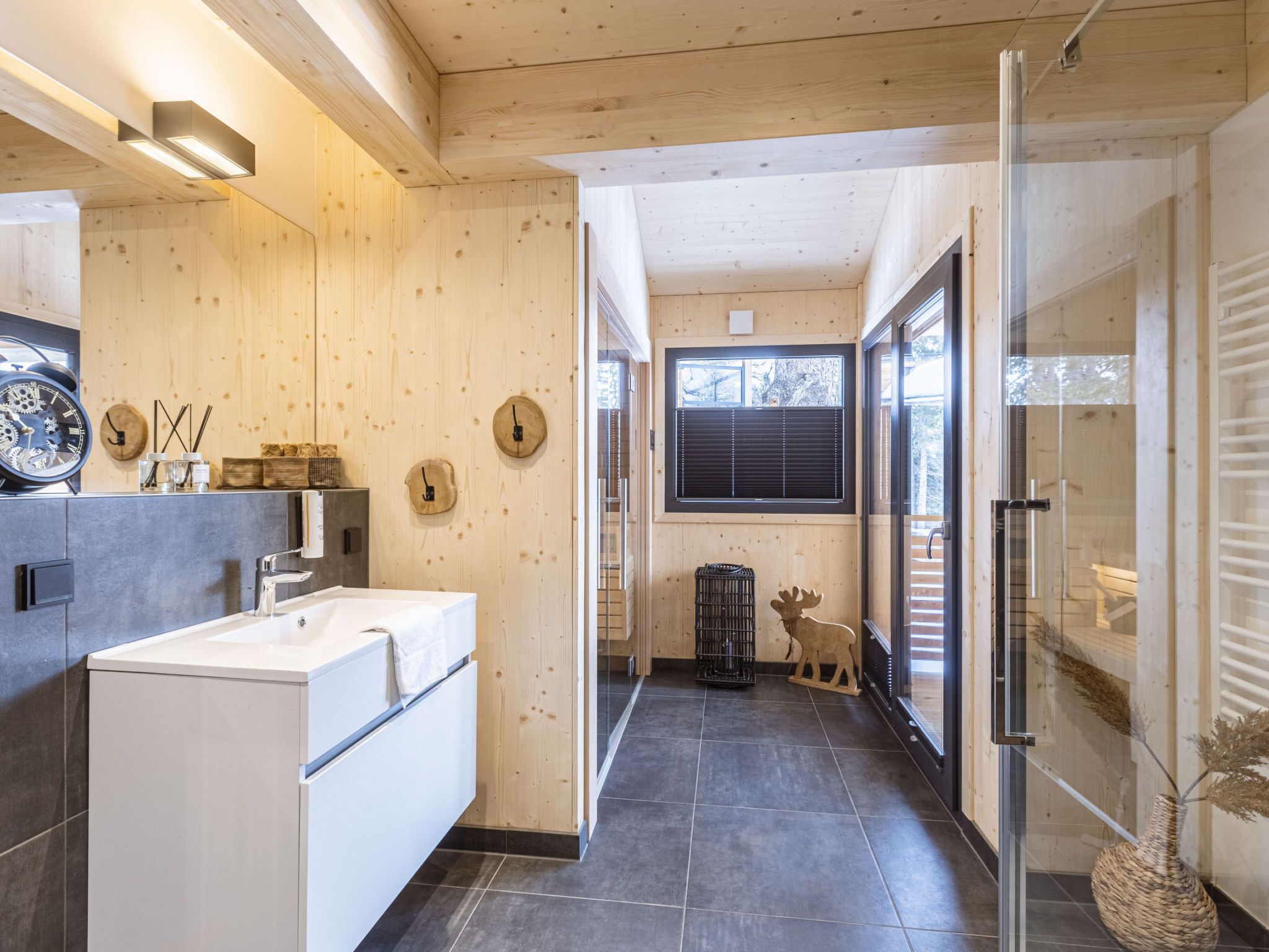 Een moderne badkamer met een witte wastafel, houten wanden en een glazen douchecabine.
