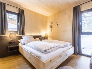 Una habitación de madera con una cama, dos mesitas de noche, una lámpara de pared y una decoración con estrellas.