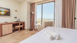 A hotel room with a bed, a desk, a chair, a TV, and a view of the outdoors. - Kyriad Muscat (Muscat)