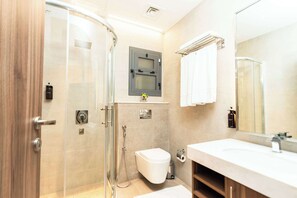 A modern bathroom with a glass shower enclosure, a toilet, and a sink with a mirror. - Kyriad Muscat (Muscat)