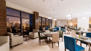 A modern hotel lobby with spacious seating areas, large windows, and contemporary lighting fixtures. - Kyriad Muscat (Muscat)