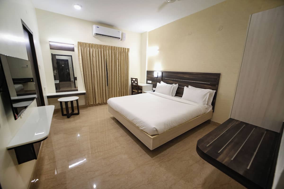 Hotelkamer met een bed, bureau, stoel, televisie en airconditioning.