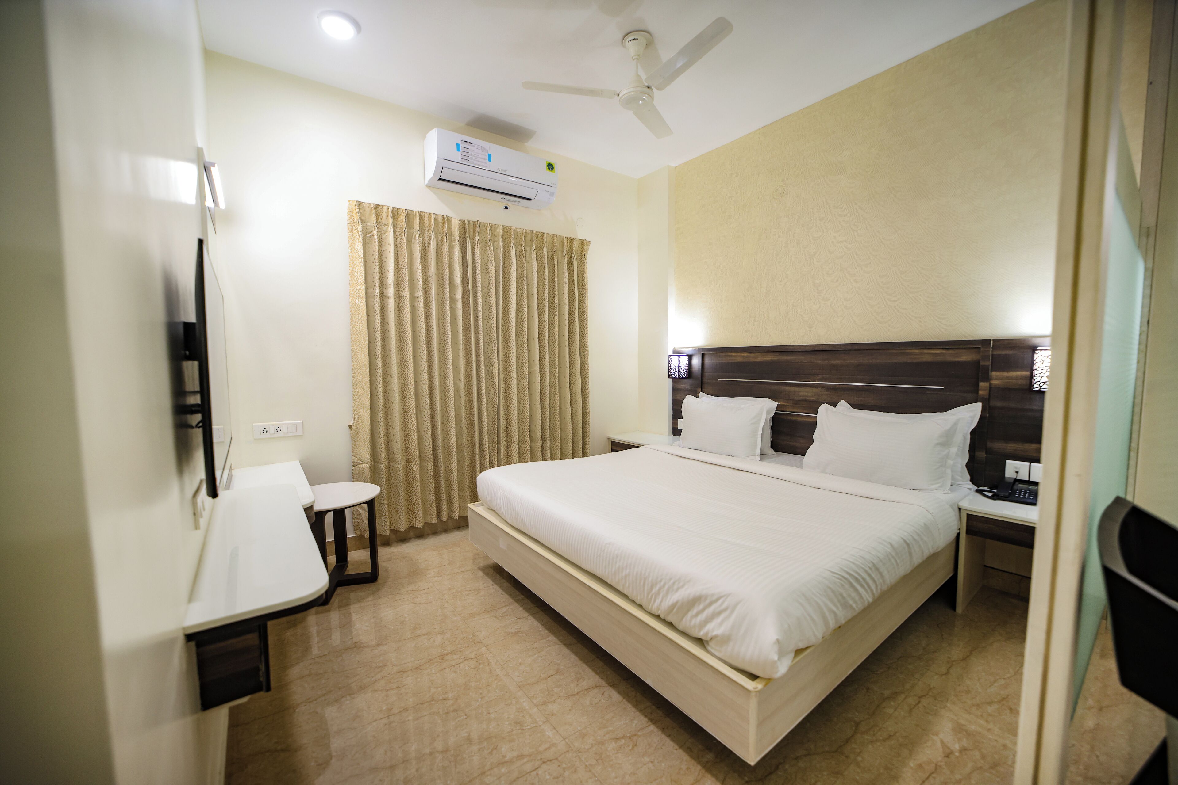 A hotel room with a bed, bedside table, chair, and a ceiling fan.