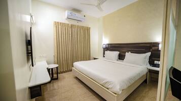 A hotel room with a bed, bedside table, chair, and a ceiling fan.