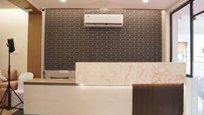Una zona de recepción con un mostrador de mármol, un papel tapiz decorativo y un equipo de aire acondicionado.