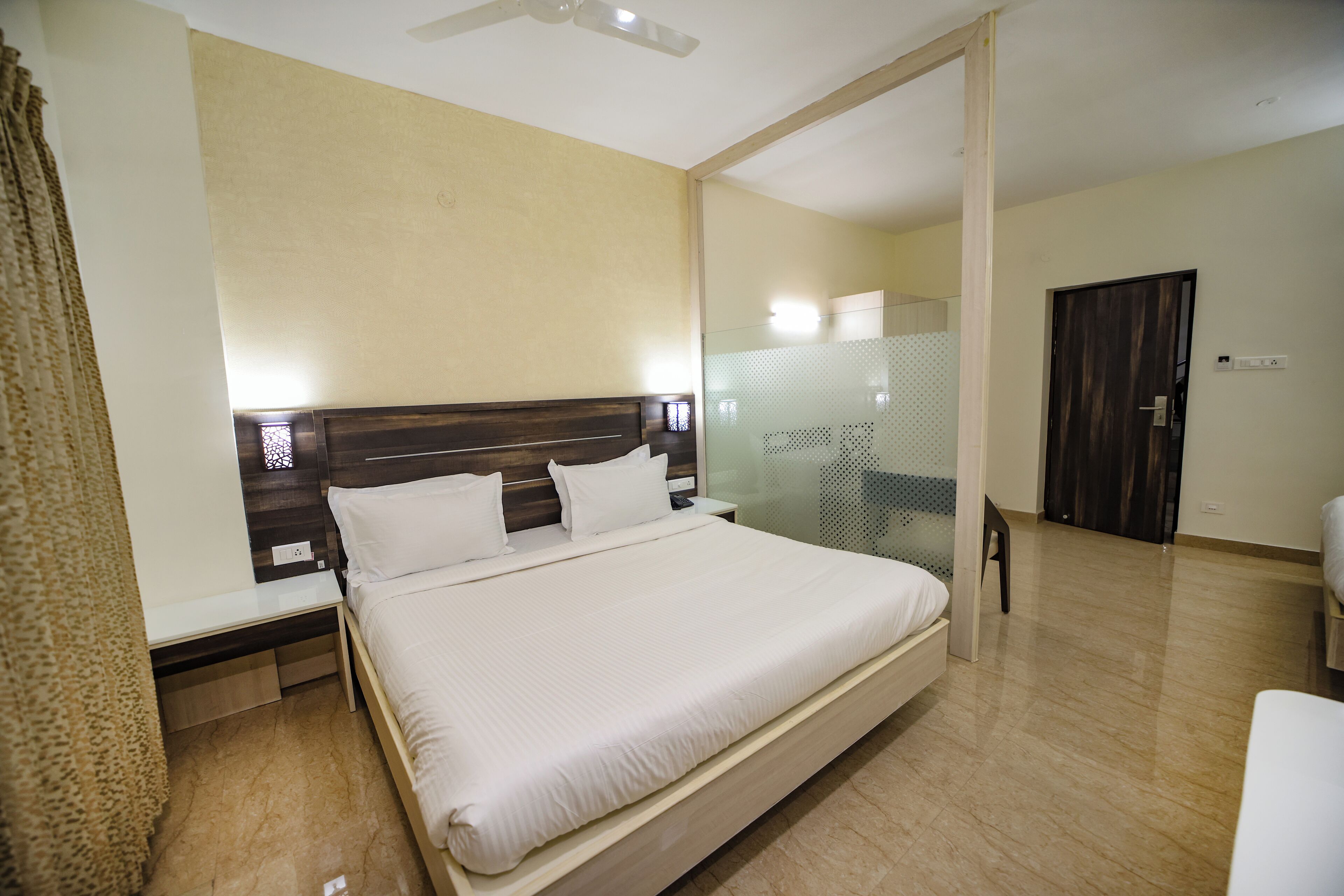 Ein Hotelzimmer mit einem großen Bett, Nachttischen, einem Spiegel und einer Tür.