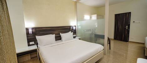 Ein Hotelzimmer mit einem großen Bett, Nachttischen, einem Spiegel und einer Tür.