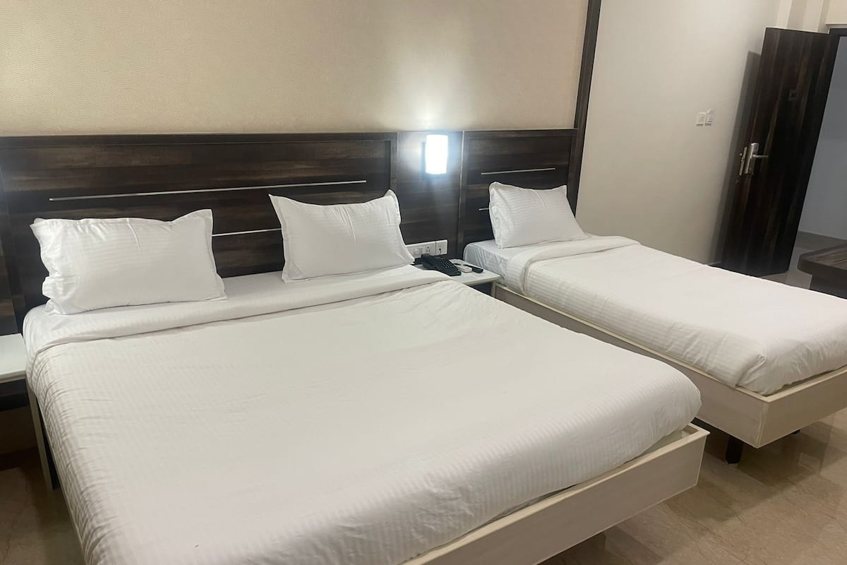 Een hotelkamer met twee bedden, elk met witte beddengoed en een houten hoofdeinde.
