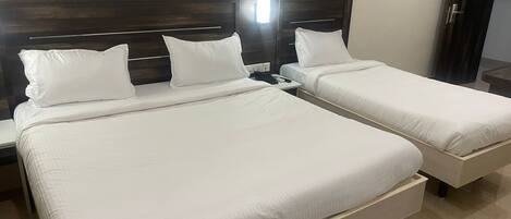 A hotel room with two beds, each with white bedding and a wooden headboard.
