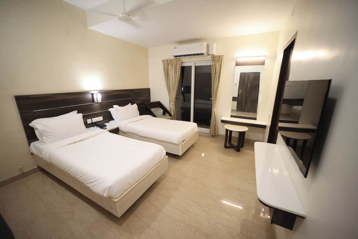 Een hotelkamer met twee bedden, een bureau, een stoel, een spiegel en een airconditioning.