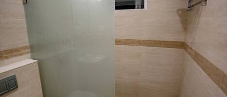 A bathroom with a glass shower enclosure, a toilet, and a towel rack.
