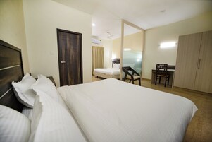 Une chambre d’hôtel avec un grand lit, un bureau avec une chaise, une armoire et un miroir.