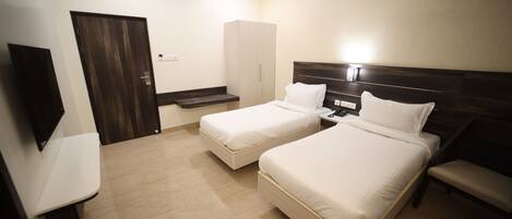 A hotel room with two beds, a wardrobe, a TV, and a bench.