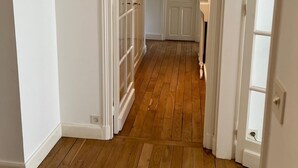 A hallway with wooden flooring, white walls, and a door leading to a bathroom. - Quite, Lovely Apartment in Paris (Paris)