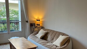A living room with a sofa, a wooden table, a rug, and a lamp. - Quite, Lovely Apartment in Paris (Paris)