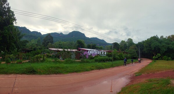 A rural road with a signboard, greenery, and mountains in the background. - Phulunngkhawiew Homestay (Bung Khong Long)