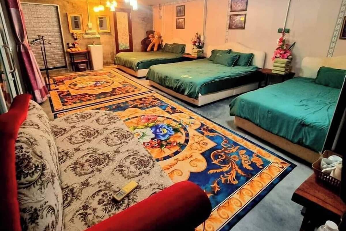 Quarto com duas camas de solteiro, um sofá, um tapete estampado e uma pequena mesa com uma chaleira.