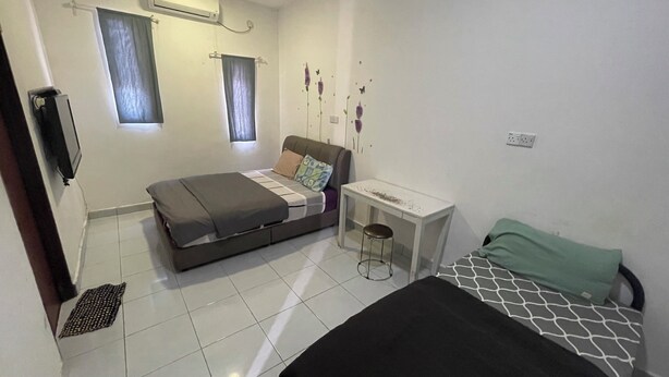 Una habitación pequeña y limpia con cama, una mesita y una ventana con cortinas.