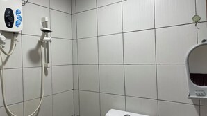 Un baño con paredes de azulejos blancos, una ducha e inodoro.