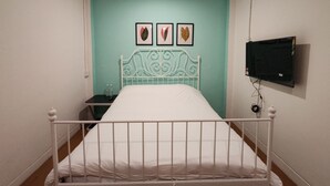 A bedroom with a white metal bed frame, a teal wall, and a flat-screen TV mounted on the wall. - SongTam Hotel  (Ipoh)