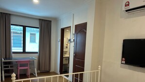A room with a bed, a desk with a chair, a window with curtains, a door, and a wall-mounted air conditioner. - SongTam Hotel  (Ipoh)