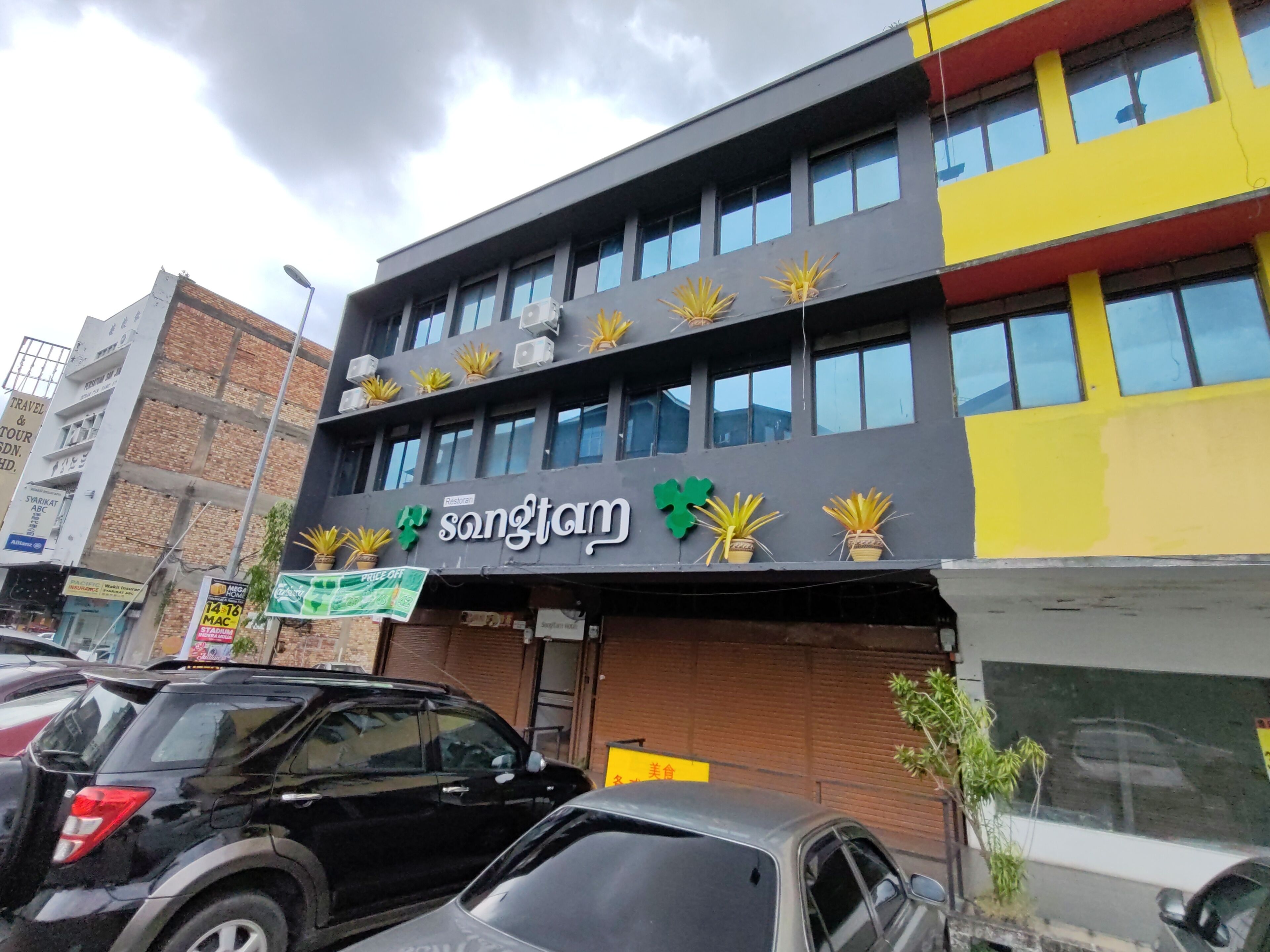 Un edificio con un restaurante llamado 'Songtam' en la planta baja, adornado con macetas en los alféizares de las ventanas.