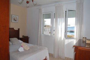 A bedroom with a bed, a nightstand, a dresser, and a window with curtains. - Casa Mariño (Goyanes)