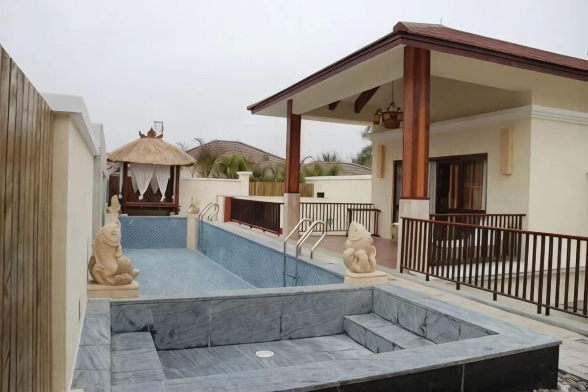 A swimming pool with a sunken seating area, a covered patio, and a decorative gazebo.