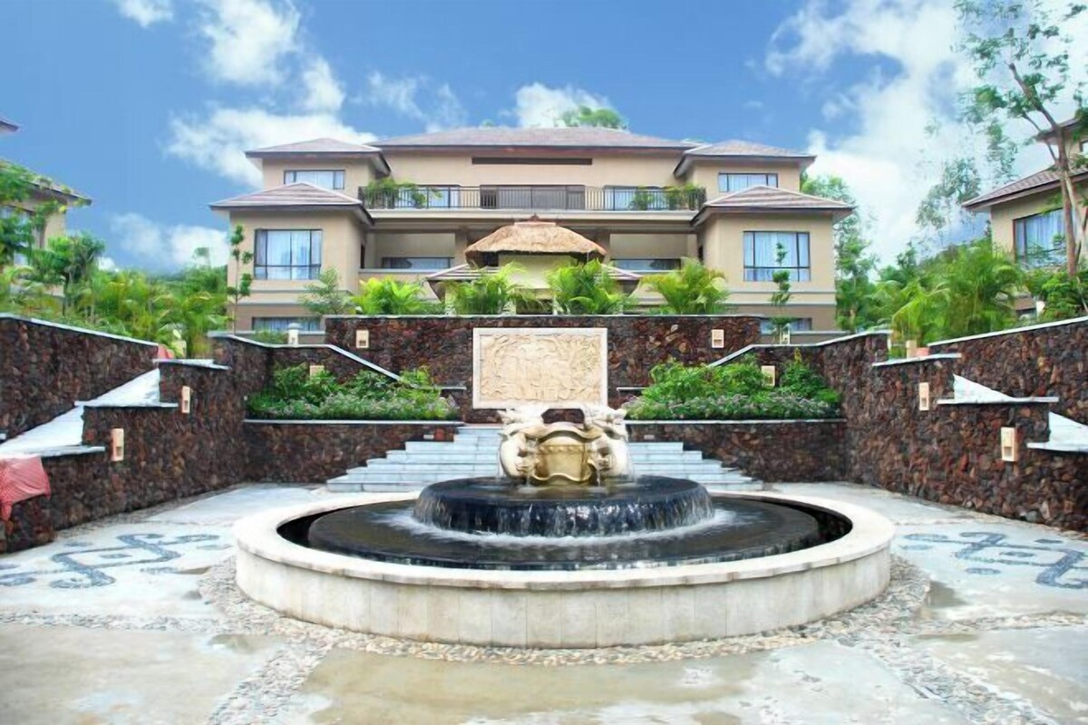 A hotel with a central fountain, stone walls, and a large building with multiple balconies.