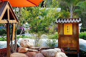 Una parrilla japonesa tradicional al aire libre con rocas y una estructura de madera, rodeada de follaje.