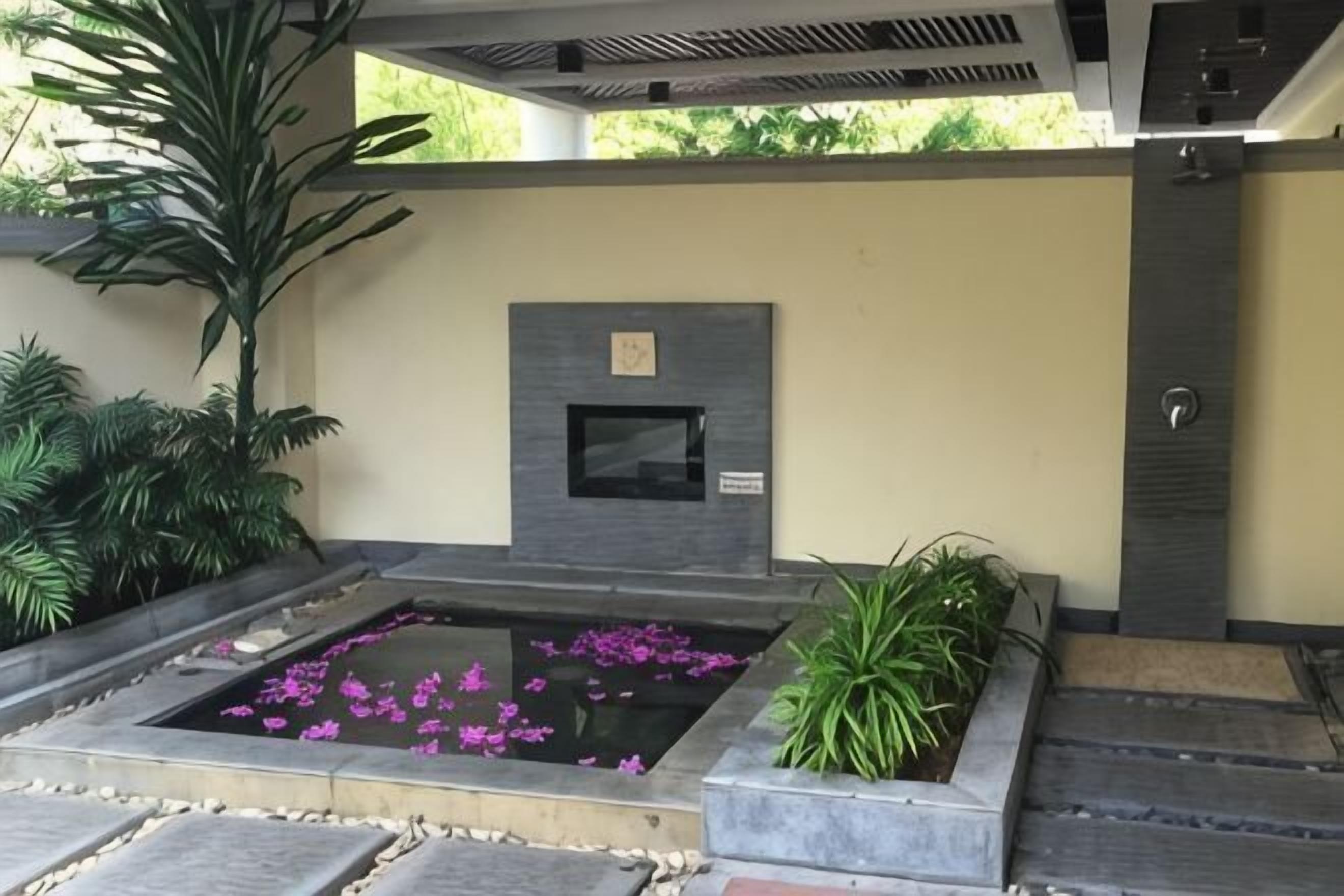 A modern outdoor area with a stone water feature, a planter with green plants, and a stone bench.