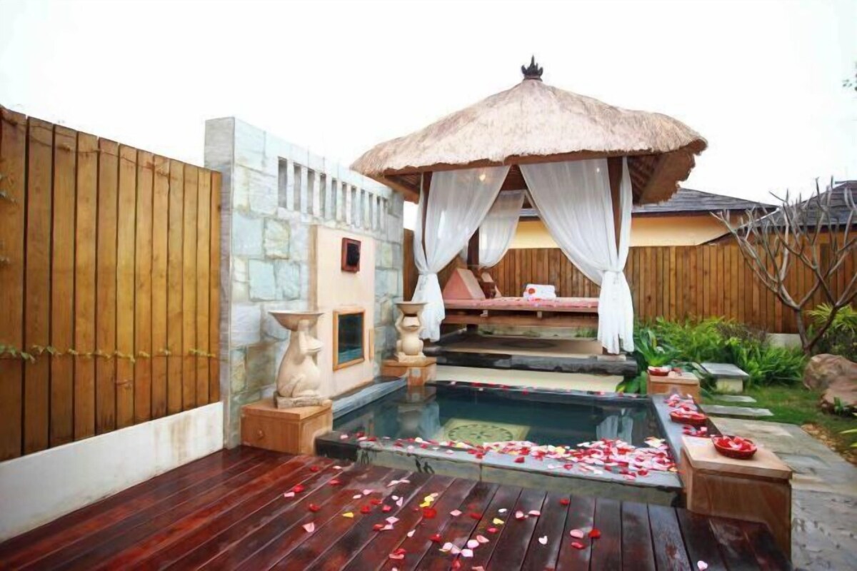 A spa area with a hot tub, wooden deck, and a gazebo with a canopy.