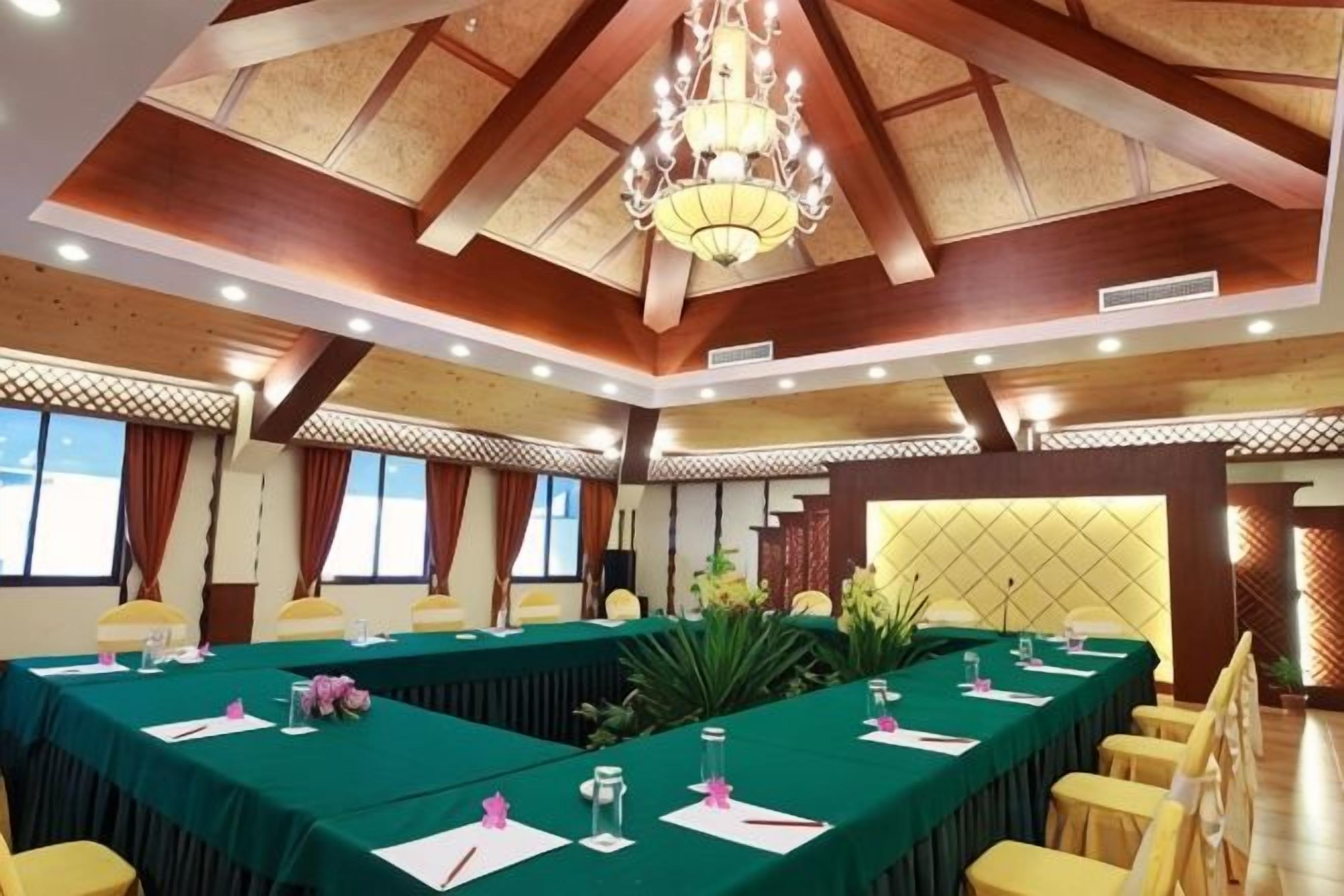 Un salón de conferencias con una larga mesa, sillas amarillas y una lámpara de araña.