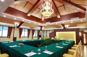 A conference room with a long table, yellow chairs, and a chandelier.