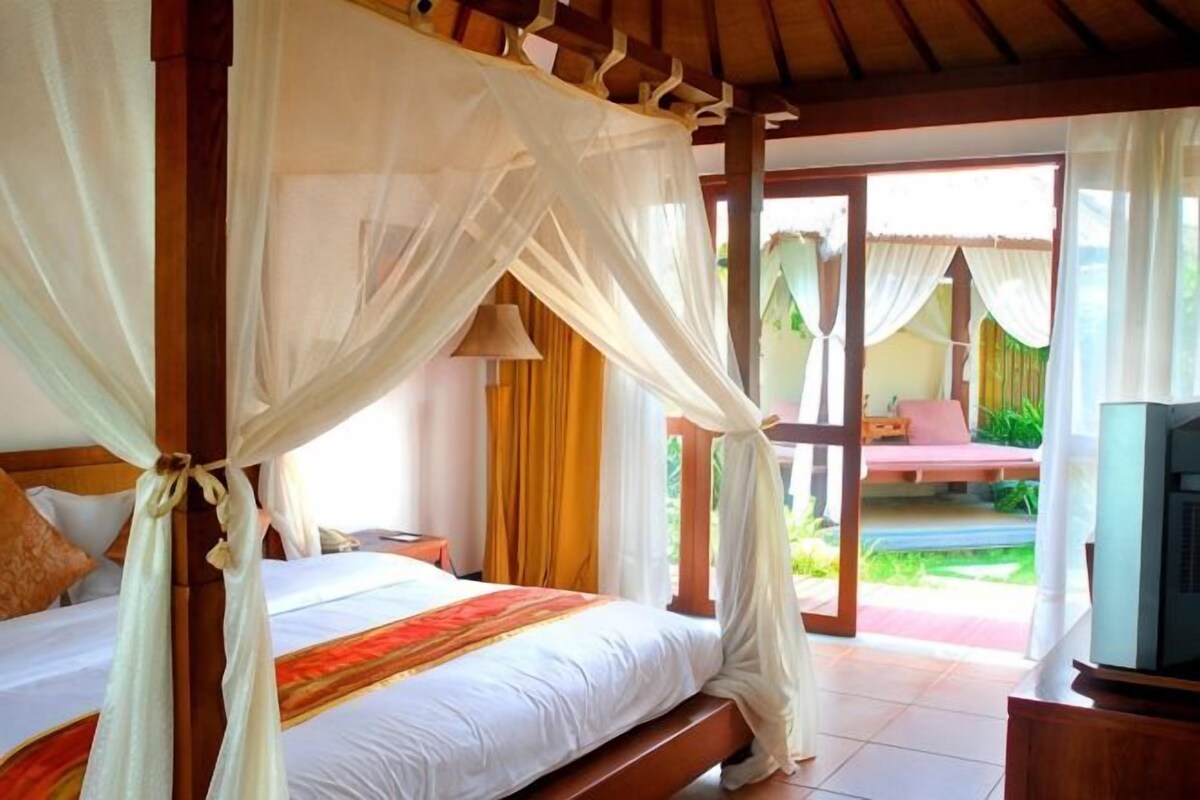 A bedroom with a canopy bed, a television, and a view of the garden.