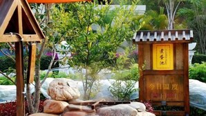 Una struttura in legno tradizionale con una targa, circondata da rocce e vegetazione.