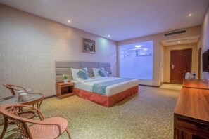 Una habitación de hotel con cama, una mesita con sillas, televisión y ventana con vistas.