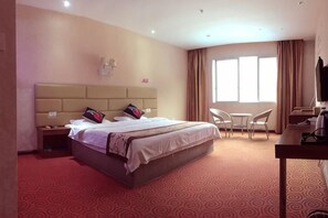 A hotel room with a large bed, a desk, a chair, and a TV. - Kerry Garten Fashion Hotel (Kaili)